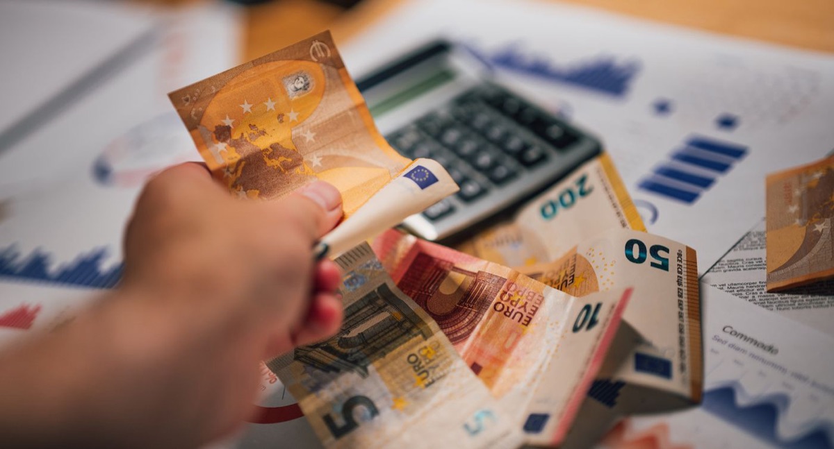 Billetes de euro sobre documentos financieros con una calculadora