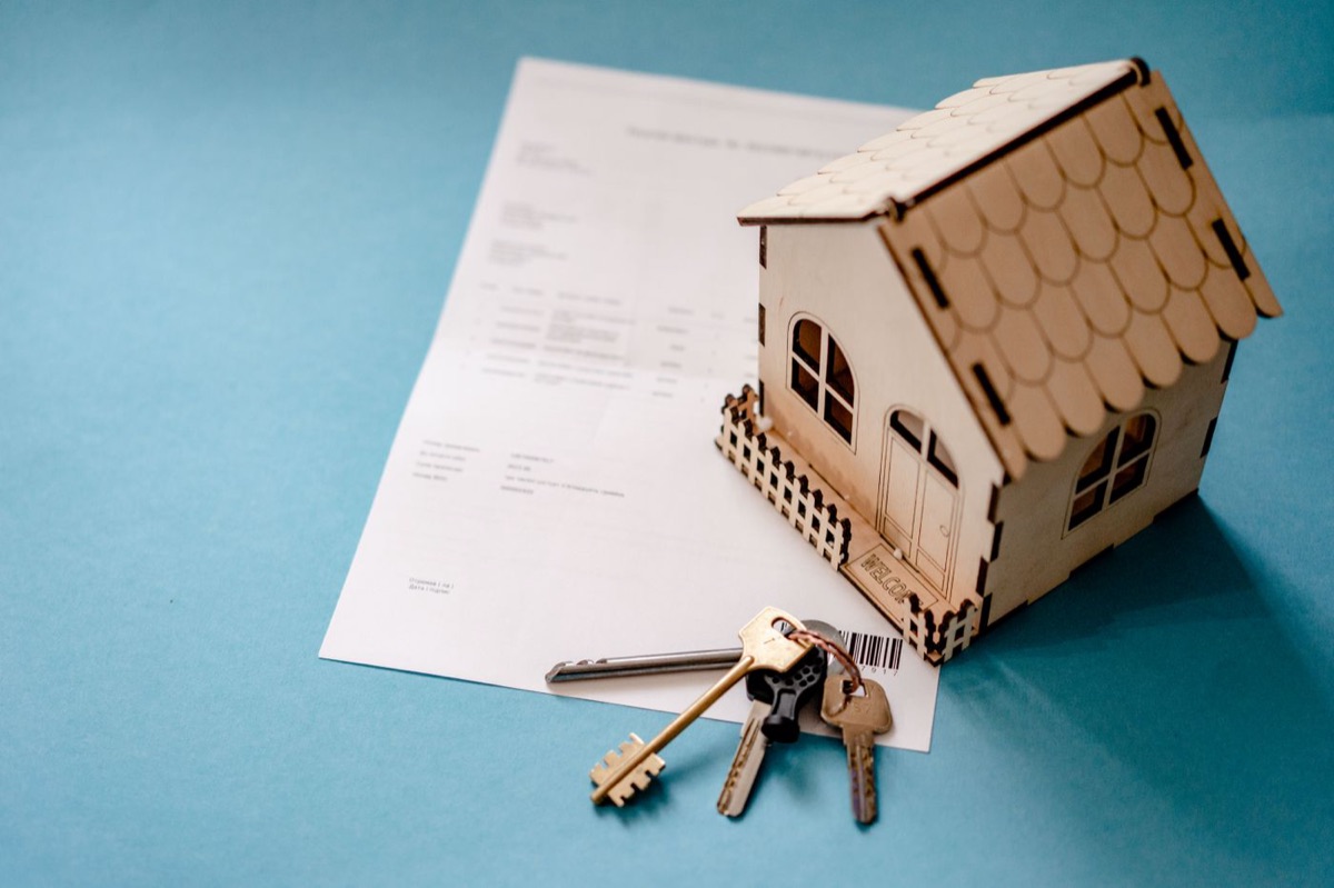 Casa en miniatura con llaves y un contrato de préstamo hipotecario